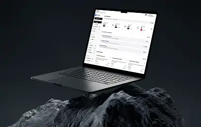 A floating laptop above a rocky surface on a dark background, showing a web dashboard interface with a left sidebar and a list-style workspace on the screen.